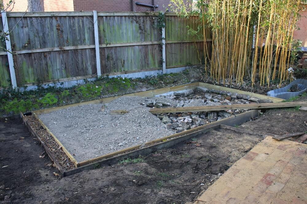 Timber shuttered base being filled with compacted hardcore in a rear garden