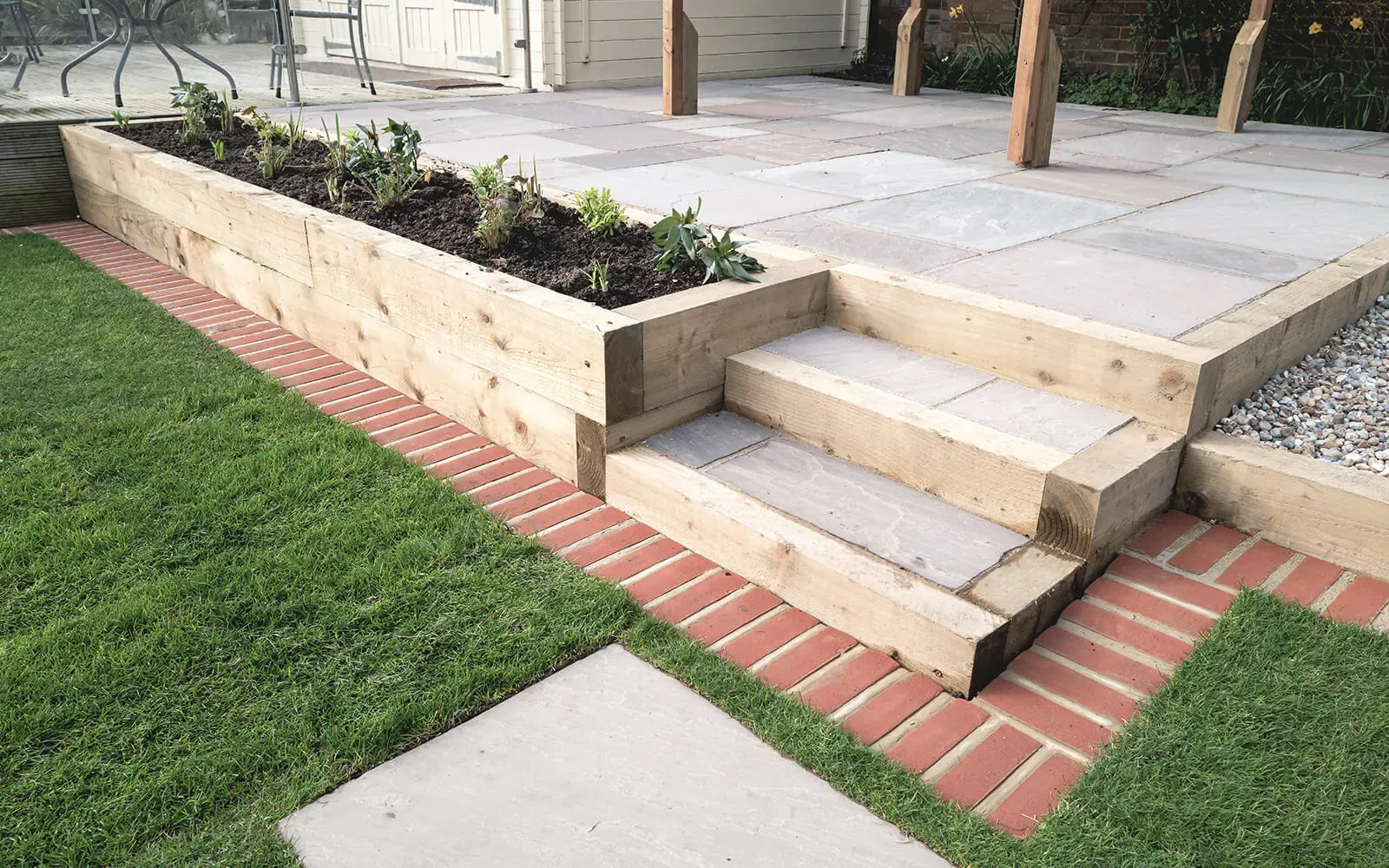 Curved block paved path edged against a new lawn and planted borders