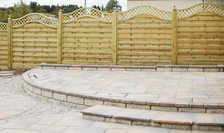 Decorative wave top panel fencing above a curved block edged patio with steps