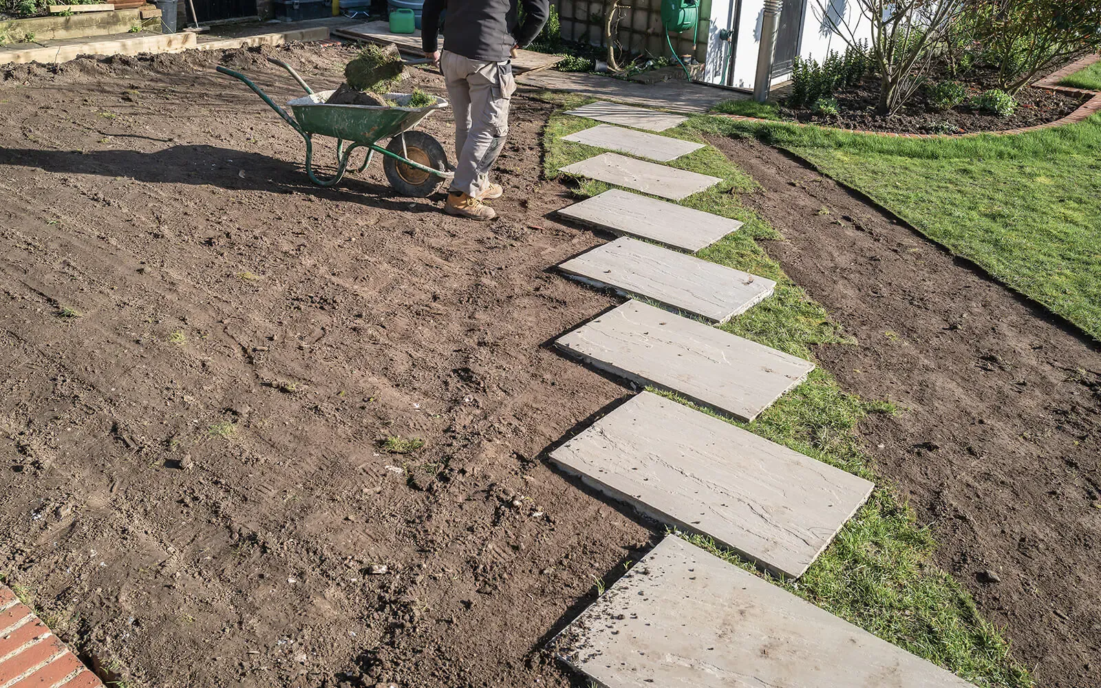 New lawn with sandstone stepping stones and sleeper-edged gravel border